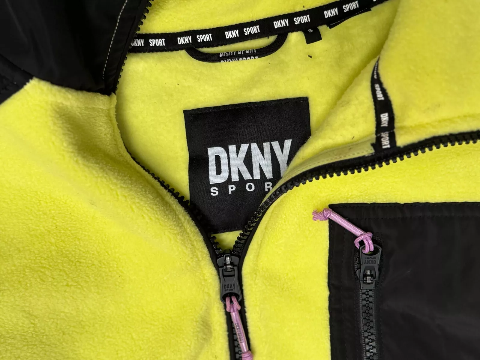 Close-up of DKNY Sport fleece jacket label and zip detail with yellow fleece fabric