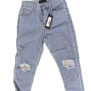 Full view of I Saw It First ripped knee jeans with tags, laid flat on green background.